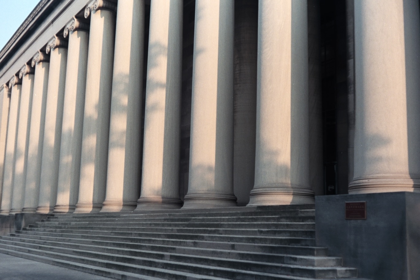 Large cement pillars with shadows of nearby trees showing across them.