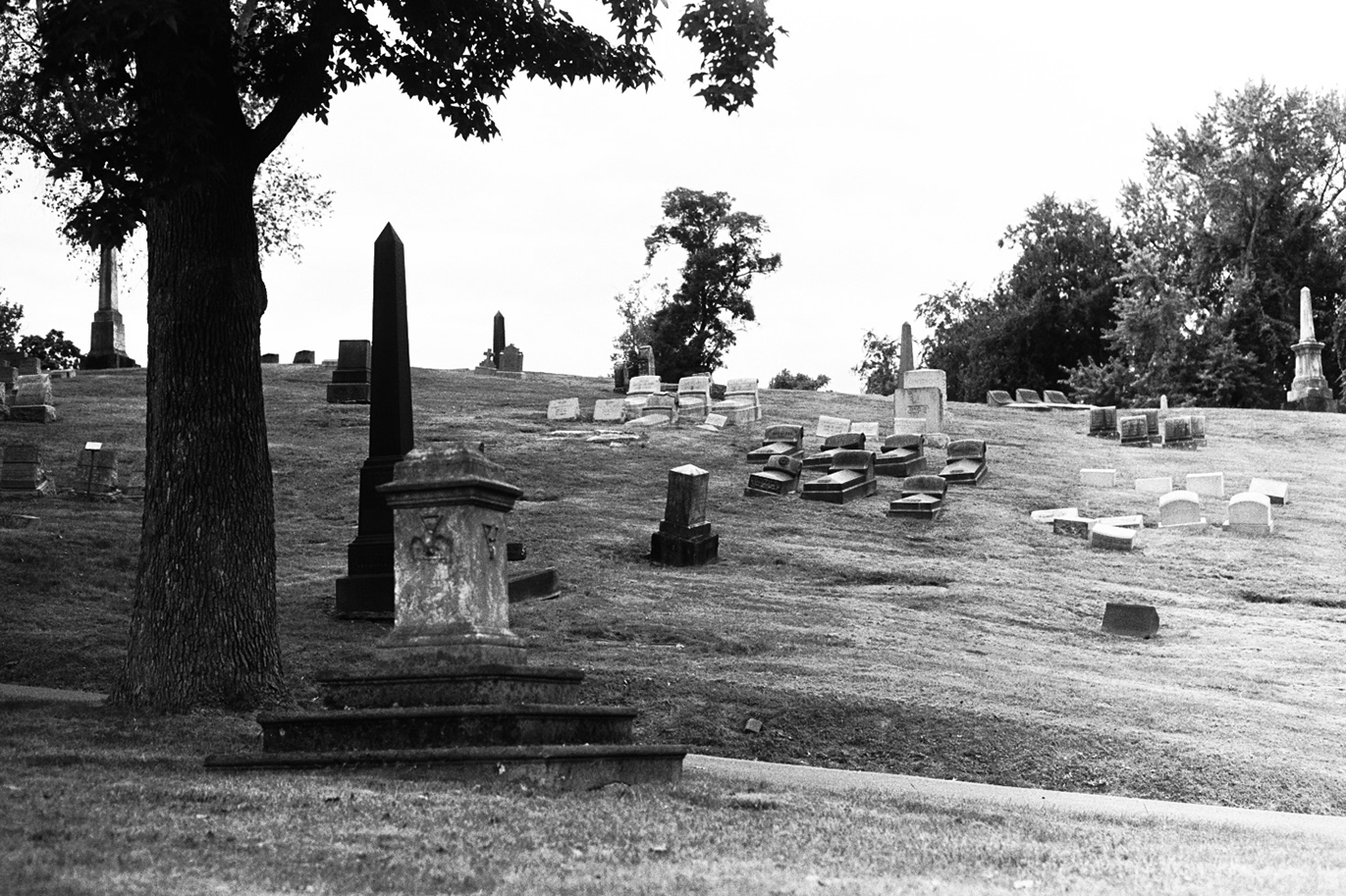 Various gravestones and monuments on a hill in black and white.